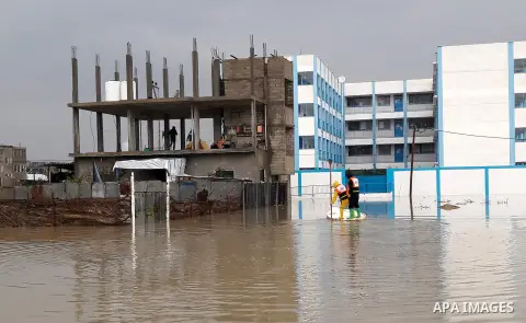Palestinian Civil Defence workers use a stand-up kayak to evacuate people from a flooded area following heavy rainfall in the southern Gaza Strip town of Rafah on January 26, 2016. Photo by Abed Rahim Khatib