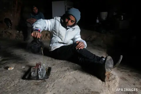 A Palestinian boy pours tea as he sits with his family inside a cave they live in, during a snow storm in West Bank village of Mufagara, south of Hebron January 27, 2016. Photo by Wisam Hashlamoun