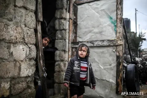 A picture taken on January 25, 2016 shows A Palestinian girl stands on her family's doorstep looking at a flooded street following heavy rainfall in Khan Younis in the southern Gaza Strip. Photo by Mohammed Dahman