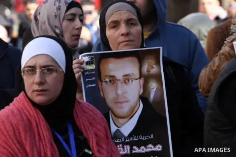 Palestinians hold pictures of journalist Mohammed al-Qeq, who has been on a hunger strike in an Israeli jail for 65 days, during a protest to show solidarity with him, in the West bank city of Nablus, on January 28, 2016...