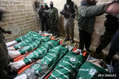 Palestinian members of Ezzedeen al-Qassam, the armed wing of Hamas movement, sit next to the bodies of Palestinian Hamas militants whom killed after a tunnel, built for fighting Israel, collapsed in the Gaza Strip, durin...