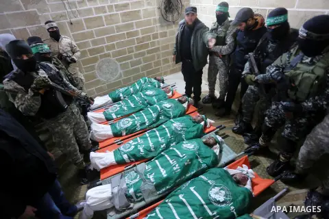 Palestinian members of Ezzedeen al-Qassam, the armed wing of Hamas movement, sit next to the bodies of Palestinian Hamas militants whom killed after a tunnel, built for fighting Israel, collapsed in the Gaza Strip, durin...