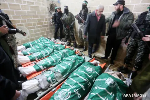 Palestinian members of Ezzedeen al-Qassam, the armed wing of Hamas movement, sit next to the bodies of Palestinian Hamas militants whom killed after a tunnel, built for fighting Israel, collapsed in the Gaza Strip, durin...