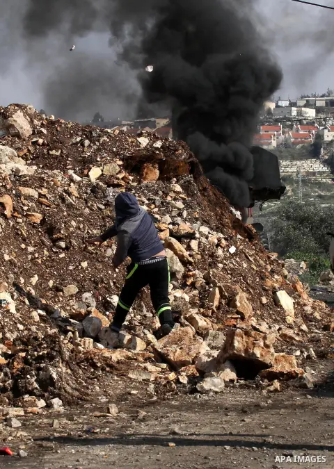 A Palestinian protester hurls stones toward Israeli security forces during clashes following a protest against the expropriation of Palestinian land by Israel in the West Bank village of Kafr Qaddum, near the northern ci...