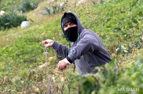 A Palestinian protester uses a slingshot to hurl stones toward Israeli security forces during clashes following a protest against the expropriation of Palestinian land by Israel in the West Bank village of Kafr Qaddum, n...