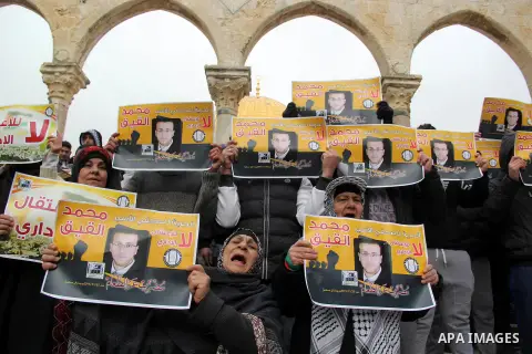 Palestinians hold posters bearing a portrait of Palestinian journalist Mohammed al-Qiq who is imprisoned in an Israeli jail during a protest in support of his hunger strike in front of Jerusalem's Dome of the Rock mosque...