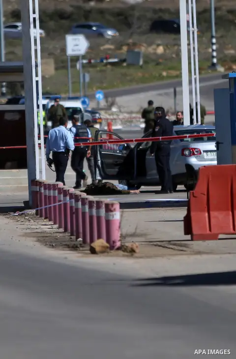 Israeli troops gather around the body of a dead Palestinian assailant at the scene of a shooting attack at an Israeli military checkpoint near the West Bank city of Ramallah January 31, 2016. Photo by Shadi Hatem