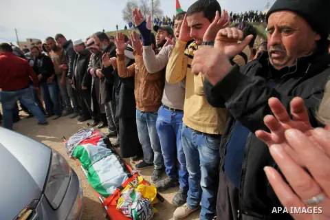 Palestinians pray in front of the body of Palestinian gunman Amjad Abu Omar, whom the Israeli army said was shot dead by soldiers after he wounded three Israelis on Sunday, during his funeral in the West Bank village of...