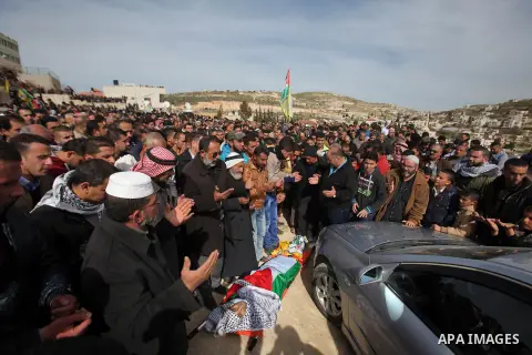 Palestinians pray in front of the body of Palestinian gunman Amjad Abu Omar, whom the Israeli army said was shot dead by soldiers after he wounded three Israelis on Sunday, during his funeral in the West Bank village of...