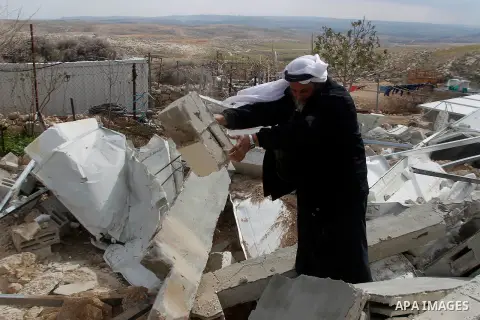 A Palestinian man collects items from his home after it was demolished by Israeli bulldozers in a disputed military zone in the area of Musafir Jenbah, which includes several villages, south of the West Bank town of Hebr...