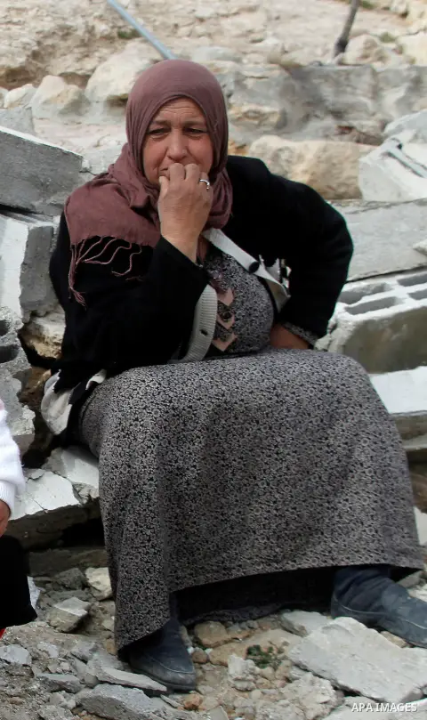 A Palestinian woman sits next on the remains of her home after it was demolished by Israeli bulldozers in a disputed military zone in the area of Musafir Jenbah, which includes several villages, south of the West Bank to...