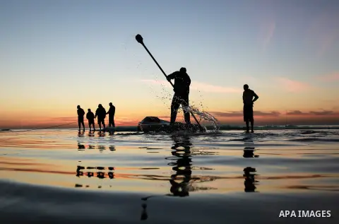 Palestinian fishermen work during the sunset on the beach of Gaza city on Feb. 04, 2016. Photo by Mohammed Dahman