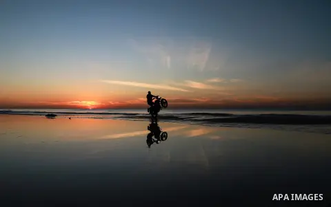 A Palestinian man rides motorcycle during the sunset on the beach of Gaza city on Feb. 04, 2016. Photo by Mohammed Dahman