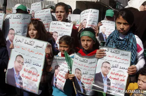 Palestinian demonstrators hold posters bearing portraits of Palestinian journalist Mohammed al-Qiq who is imprisoned in an Israeli jail during a protest in support of his hunger strike in the West Bank city of Hebron on...