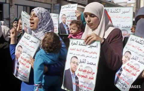 The wife of Palestinian imprisoned journalist Mohammed al-Qiq, Fayha Shalash holds a poster bearing portrait of her husband's who is imprisoned in an Israeli jail during a protest in support of his hunger strike in the W...