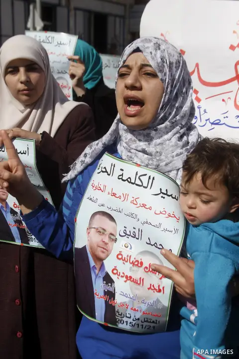 Palestinian demonstrators hold posters bearing portraits of Palestinian journalist Mohammed al-Qiq who is imprisoned in an Israeli jail during a protest in support of his hunger strike in the West Bank city of Hebron on...