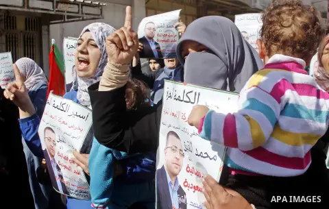 Palestinian demonstrators hold posters bearing portraits of Palestinian journalist Mohammed al-Qiq who is imprisoned in an Israeli jail during a protest in support of his hunger strike in the West Bank city of Hebron on...