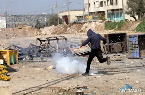 A Palestinian protester kicks back a tear gas canister fired by Israeli security forces during clashes in the Palestinian town of Qabatiya, near Jenin in the north of the Israeli-occupied West Bank, on February 5, 2016....