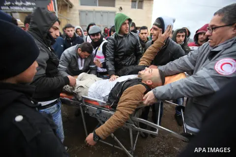 A Palestinian demonstrator runs to help his injured comrade during clashes with Israeli security forces in the village of Qabatiya, near the West Bank town of Jenin, during clashes on February 6, 2016. Three Palestinians...
