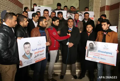 Palestinian journalists hold posters bearing portraits of Palestinian journalist Mohammed al-Qiq who is imprisoned in an Israeli jail during a protest in support of his hunger strike in Rafah in the southern Gaza strip o...