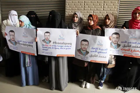Palestinian journalists hold posters bearing portraits of Palestinian journalist Mohammed al-Qiq who is imprisoned in an Israeli jail during a protest in support of his hunger strike in Rafah in the southern Gaza strip o...