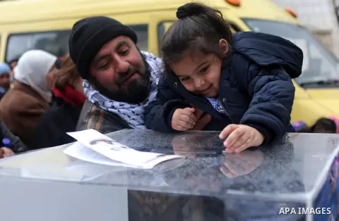 A Palestinian man holds his girl as she donates money during a fundraising campaign aimed at rebuilding the families houses of Jerusalem Martyrs, after demolished by Israeli authorities in the West Bank city of Ramallah,...