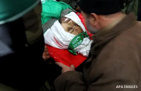 Palestinian members of the Ezzedine al-Qassam Brigades, the armed wing of the Hamas movement pray over the body of their comrade Marwan Maarouf, 27, during his funeral in Khan Yunis in the southern Gaza Strip, on Februar...