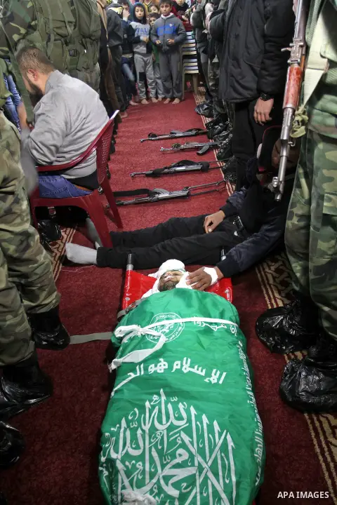 Palestinian members of the Ezzedine al-Qassam Brigades, the armed wing of the Hamas movement pray over the body of their comrade Marwan Maarouf, 27, during his funeral in Khan Yunis in the southern Gaza Strip, on Februar...