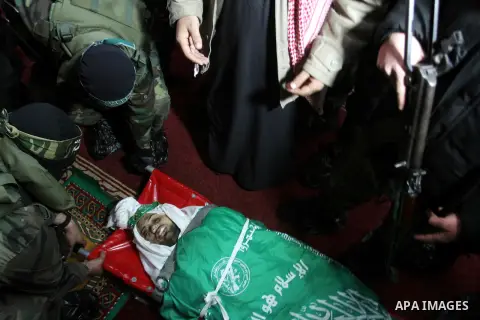 Palestinian members of the Ezzedine al-Qassam Brigades, the armed wing of the Hamas movement pray over the body of their comrade Marwan Maarouf, 27, during his funeral in Khan Yunis in the southern Gaza Strip, on Februar...