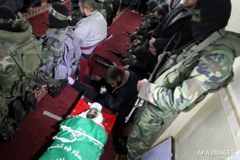 Palestinian members of the Ezzedine al-Qassam Brigades, the armed wing of the Hamas movement pray over the body of their comrade Marwan Maarouf, 27, during his funeral in Khan Yunis in the southern Gaza Strip, on Februar...
