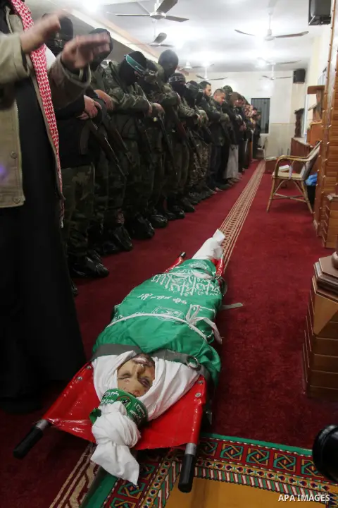 Palestinian members of the Ezzedine al-Qassam Brigades, the armed wing of the Hamas movement pray over the body of their comrade Marwan Maarouf, 27, during his funeral in Khan Yunis in the southern Gaza Strip, on Februar...