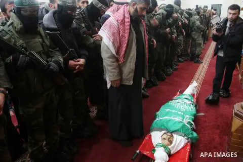 Palestinian members of the Ezzedine al-Qassam Brigades, the armed wing of the Hamas movement pray over the body of their comrade Marwan Maarouf, 27, during his funeral in Khan Yunis in the southern Gaza Strip, on Februar...