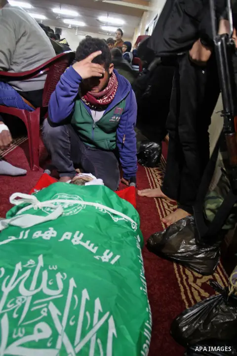 Palestinian members of the Ezzedine al-Qassam Brigades, the armed wing of the Hamas movement pray over the body of their comrade Marwan Maarouf, 27, during his funeral in Khan Yunis in the southern Gaza Strip, on Februar...