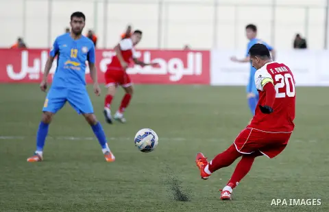 Ahly Al-Khalil football club's players (in red) and FC Khujand club's players compete during the football match crucial AFC Champions League Playoff phase at Dura Stadium in the West Bank city of Hebron on Feb. 09, 2016....