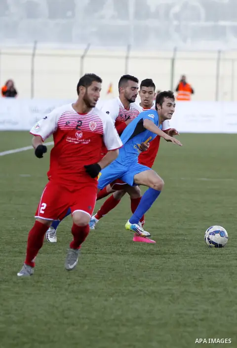 Ahly Al-Khalil football club's players (in red) and FC Khujand club's players compete during the football match crucial AFC Champions League Playoff phase at Dura Stadium in the West Bank city of Hebron on Feb. 09, 2016....