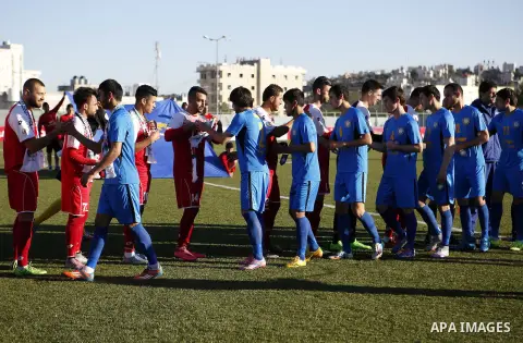 Ahly Al-Khalil football club's players (in red) shake hand with FC Khujand club's players during the football match crucial AFC Champions League Playoff phase at Dura Stadium in the West Bank city of Hebron on Feb. 09, 2...