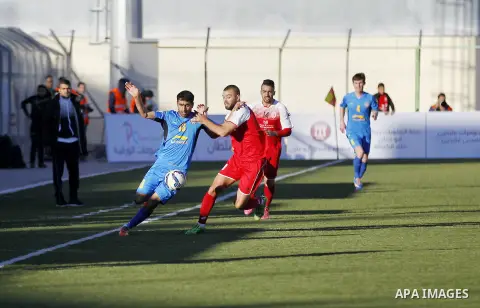 Ahly Al-Khalil football club's players (in red) and FC Khujand club's players compete during the football match crucial AFC Champions League Playoff phase at Dura Stadium in the West Bank city of Hebron on Feb. 09, 2016....