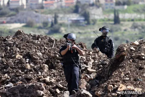 A member of Israeli security forces aims his weapon at Palestinian protesters during clashes following a protest against the expropriation of Palestinian land by Israel in the West Bank village of Kafr Qaddum, near the n...