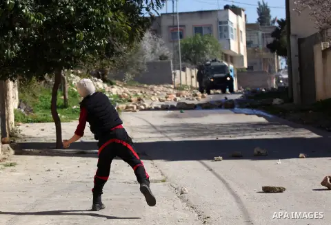 A Palestinian protester throws stones toward Israeli security forces during clashes following a protest against the expropriation of Palestinian land by Israel in the West Bank village of Kafr Qaddum, near the northern c...
