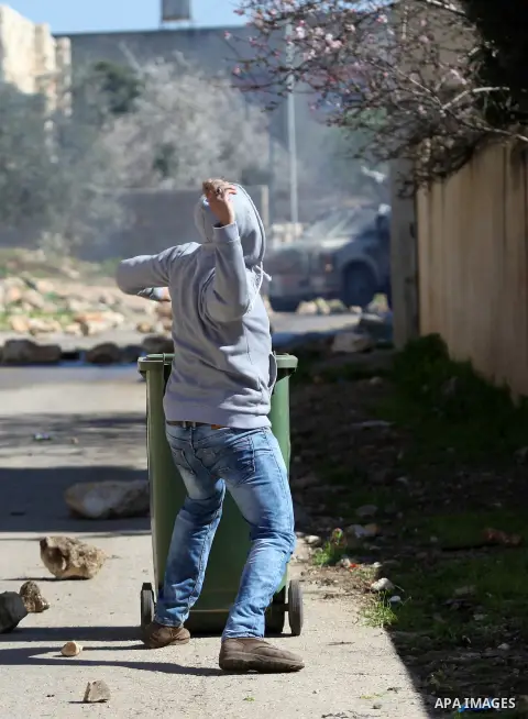 A Palestinian protester throws stones toward Israeli security forces during clashes following a protest against the expropriation of Palestinian land by Israel in the West Bank village of Kafr Qaddum, near the northern c...