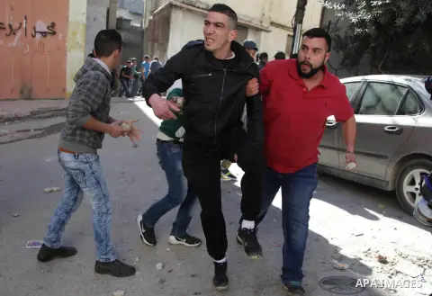 A Palestinian man, reported to be injured in the foot, is evacuated on February 15, 2016 on a street at the Amari refugee camp, near the West Bank city of Ramallah, during clashes that erupted after Israeli soldiers ente...