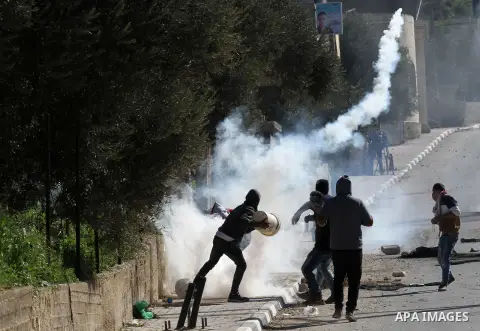 Palestinian protesters run for cover from a tear gas canister fired by Israeli security forces during clashes in the village of Araka, West of Jenin in the Israeli occupied West Bank on February 15, 2016. Photo by Nedal...