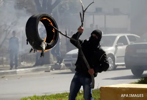 A Palestinian protester burns tires during clashes with Israeli security forces (unseen) to show solidarity with Mohammed al-Qiq a Palestinian prisoner on hunger strike, in the West bank city of Hebron on February 19, 20...
