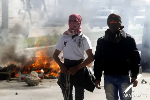 Palestinian protesters use a slingshot to hurl stones toward Israeli security forces (unseen) during clashes to show solidarity with Mohammed al-Qiq a Palestinian prisoner on hunger strike, in the West bank city of Hebro...