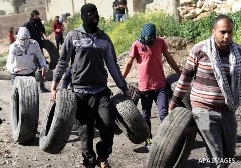 Palestinian protesters carry tires during clashes with Israeli security forces following a demonstration against the expropriation of Palestinian land by Israel on February 19, 2016 in the village of Kfar Qaddum, near Na...