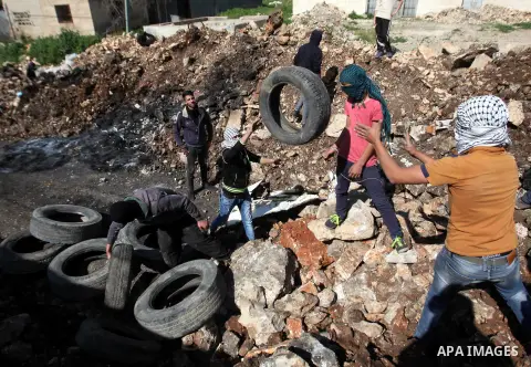 Palestinian protesters carry tires during clashes with Israeli security forces following a demonstration against the expropriation of Palestinian land by Israel on February 19, 2016 in the village of Kfar Qaddum, near Na...