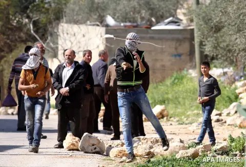 A Palestinian protester uses a slingshot to hurl stones towards Israeli security forces during clashes following a demonstration against the expropriation of Palestinian land by Israel on February 19, 2016 in the village...