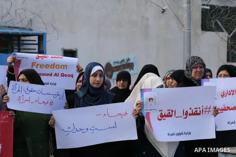Palestinian women hold posters bearing a portrait of Palestinian journalist Mohammed al-Qiq who is imprisoned in an Israeli jail during a protest in support of his hunger strike in Gaza city on Feb. 21, 2016. Photo by Mo...