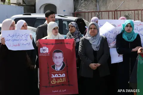Palestinian women hold posters bearing a portrait of Palestinian journalist Mohammed al-Qiq who is imprisoned in an Israeli jail during a protest in support of his hunger strike in Gaza city on Feb. 21, 2016. Photo by Mo...