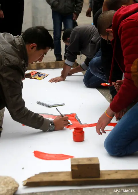 Palestinian youths paint a mural to mark the 22nd anniversary of the massacre of 29 Palestinian Muslim worshipers by Jewish extremist Baruch Goldstein at the Tomb of the Patriarchs on February 25, 1994 in the West Bank c...
